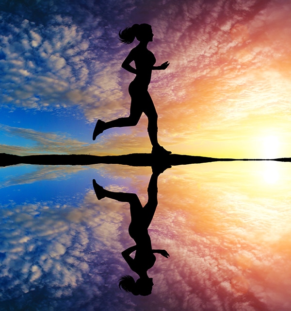 Girl running at sunset with reflection in water